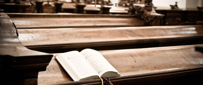 Bible with Colored Ribbon Bookmarks Open on Wooden Pew